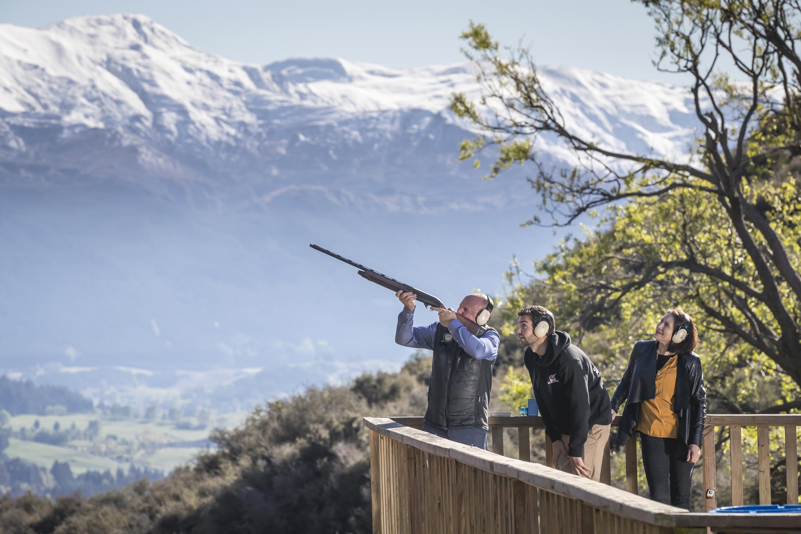 Break One Clay Target Shooting Instructor helping man fire gun with beautiful Queenstown mountains in background