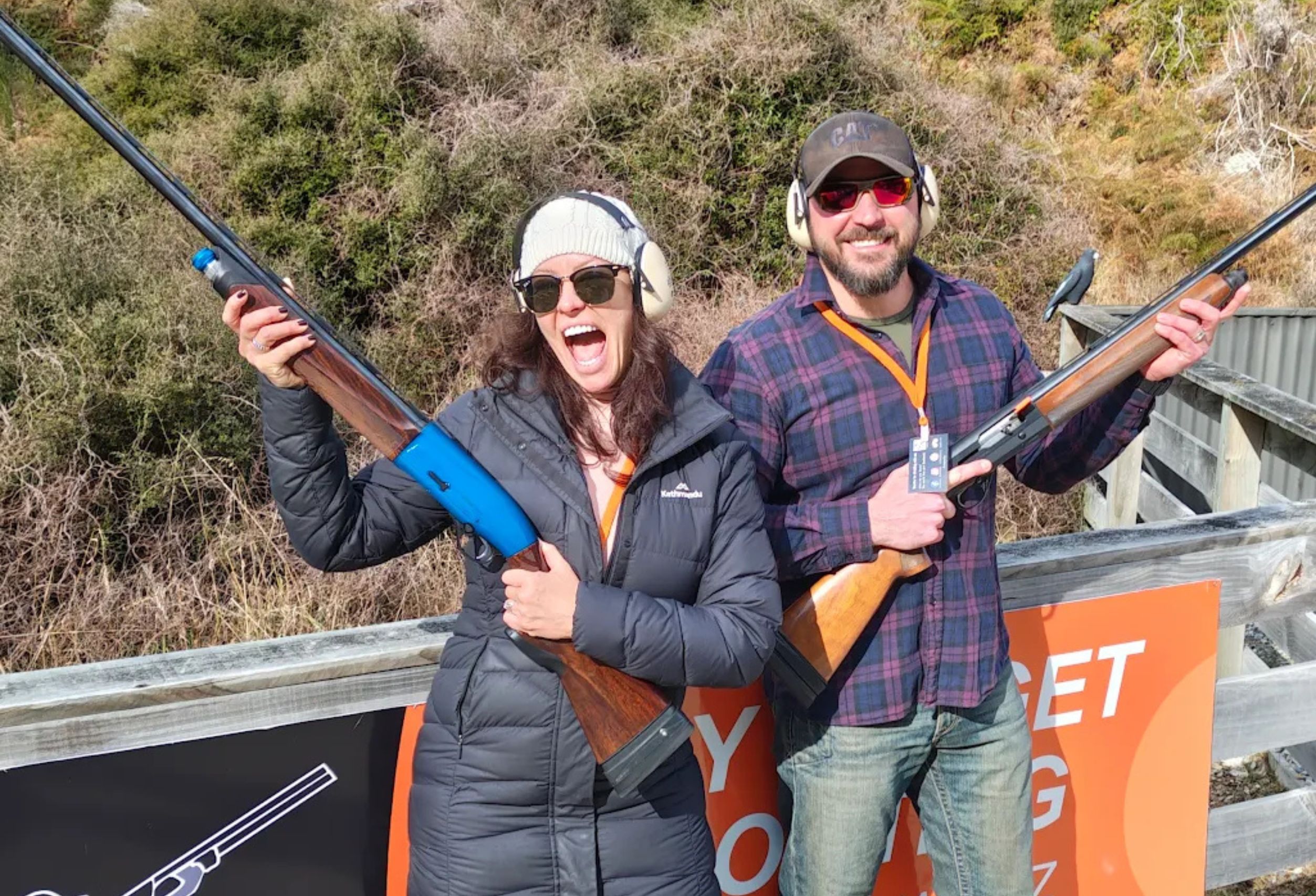 Couple posing with shotguns after a clay target shooting experience at Break One in Queenstown, smiling and celebrating a fun and supportive session.
