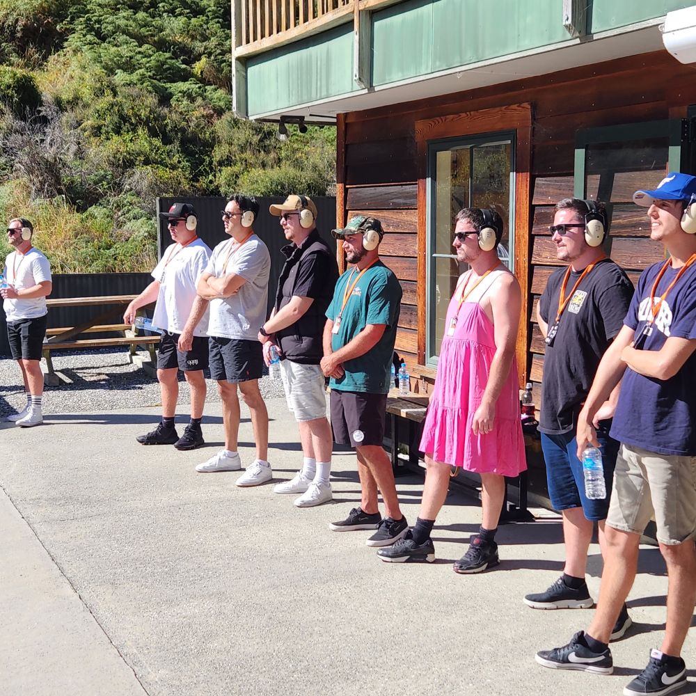 Group laughing and shooting clay targets with shotguns on Queenstown hills