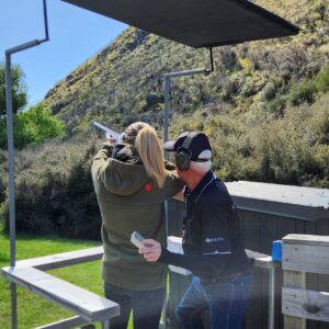 Female guest guided by an experienced instructor while shooting clay targets at Break One Clay Target Experience in Queenstown, ensuring a safe and enjoyable experience for all.